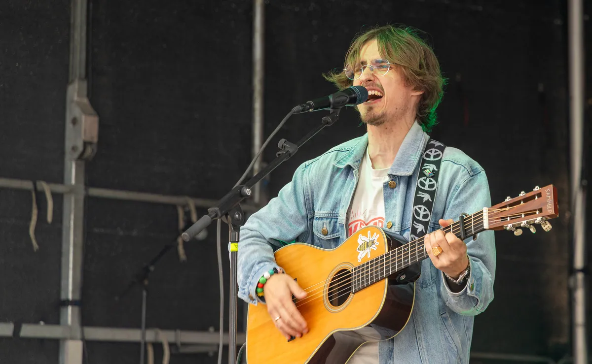 Jonas Mačys synger og spiller akustisk guitar i denimjakke
