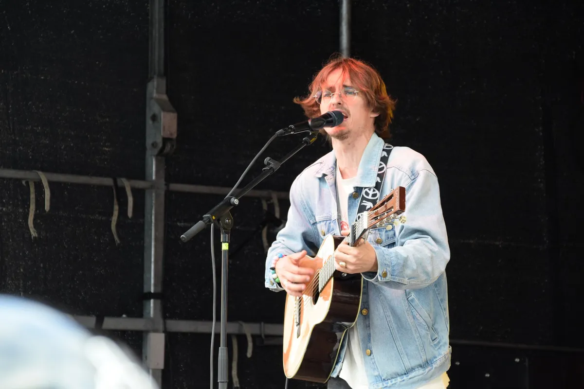 Jonas Mačys synger på scenen med rødbrunt hår og guitar