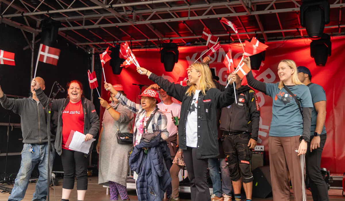 Flere personer på scenen vifter med Dannebrogsflag