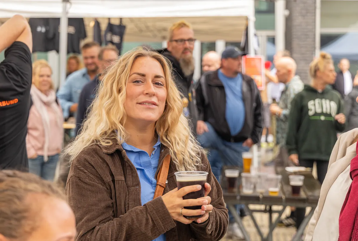Smilende kvinde med en øl i hånden