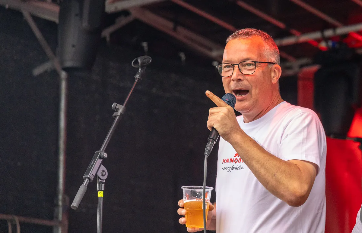 Taler med mikrofon og et glas øl på scenen